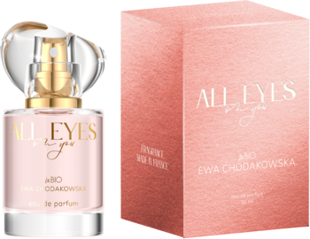 Butelka wody perfumowanej All Eyes on you z różowym płynem i złote detale, obok różowe pudełko, widok pod kątem.