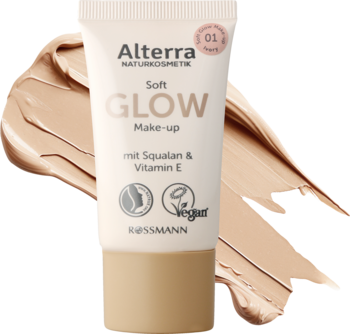 Beżowa tuba podkładu Alterra Soft Glow Make-up 01 Ivory, z białym korkiem, na tle rozmazanych próbek produktu.