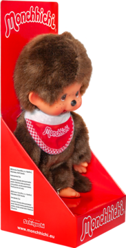 Pluszak Monchhichi, brązowa małpka z czerwonym śliniakiem w kratkę, w czerwonym tekturowym pudełku, widok z przodu.