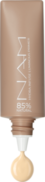Tubka beżowego primera NAM Hydra Infuse Luminous, z którego wyciska się kremowy, rozświetlający produkt.