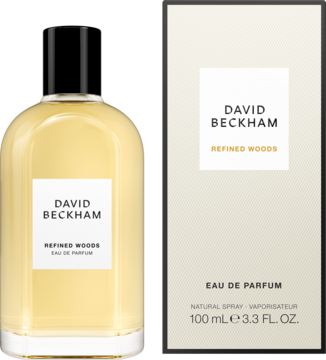 David Beckham Refined Woods męska woda perfumowana, bursztynowa butelka z czarną nakrętką i beżowe opakowanie.