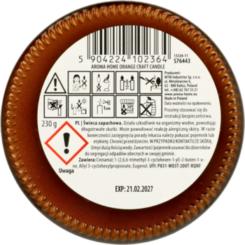 Spód pomarańczowej świecy zapachowej Aroma Home, z białą etykietą, kodem kreskowym i instrukcjami.
